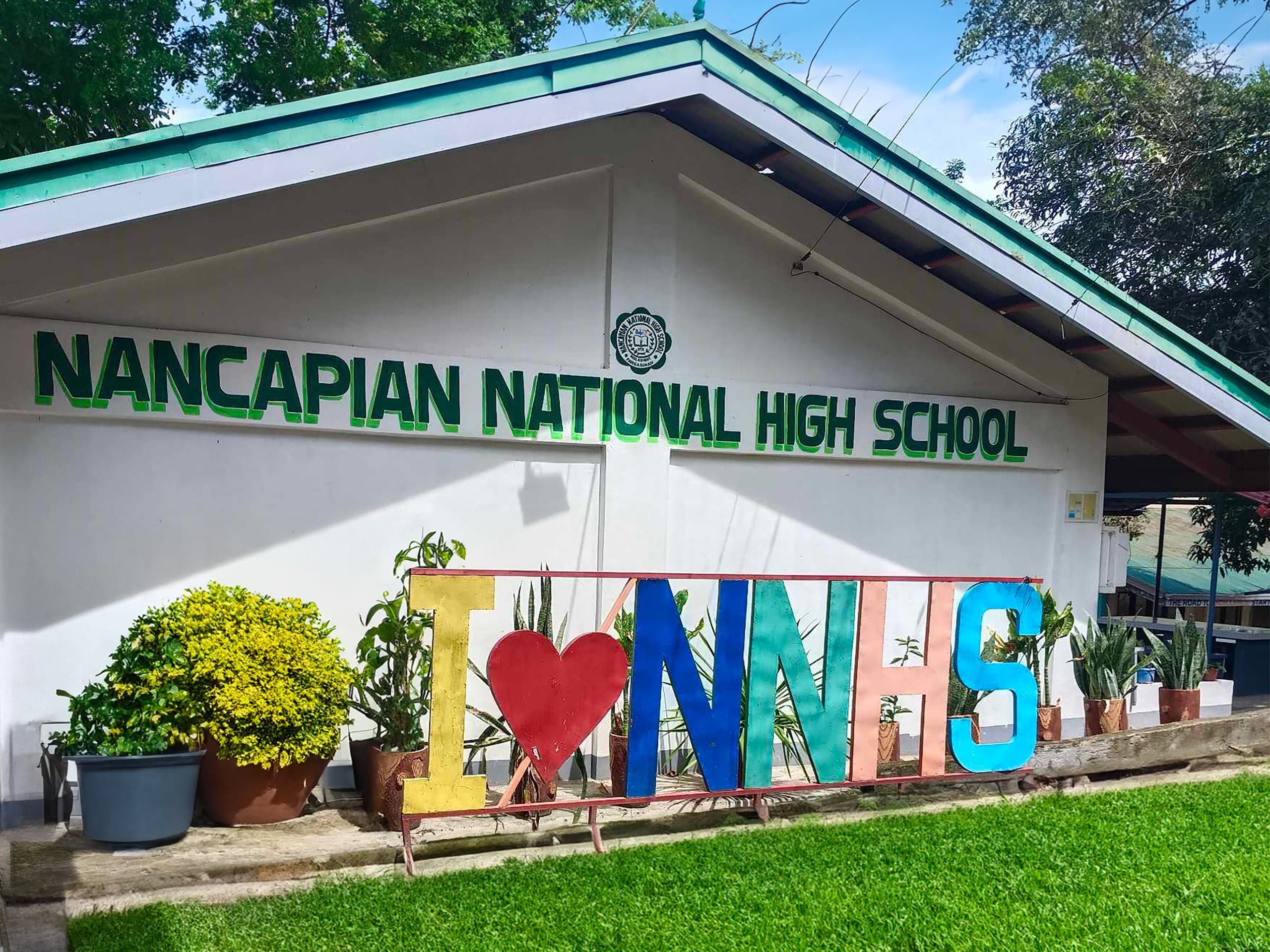 The main building of Nancapian National High School, its name painted in green letters across the front wall beneath the school seal.